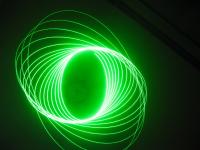 Long exposure of a green laser pointer hanging from the ceiling and pointing at the ground
